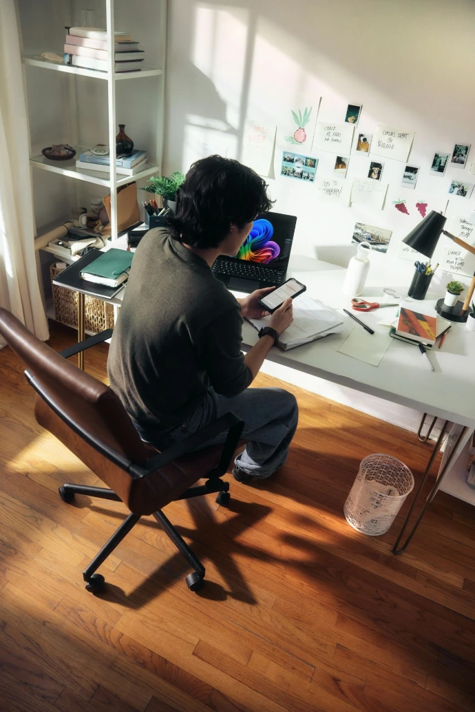 Man working at desk with laptop and phone.